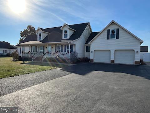 view of front facade with covered porch, a front yard, and a garage