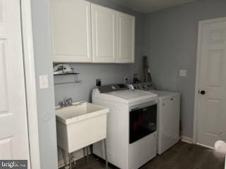 laundry area featuring washer and dryer, dark hardwood / wood-style floors, cabinets, and sink