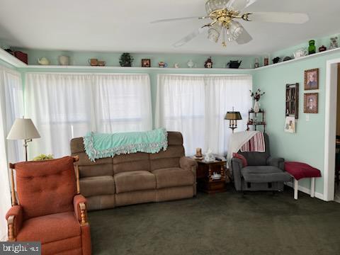 carpeted living room with ceiling fan