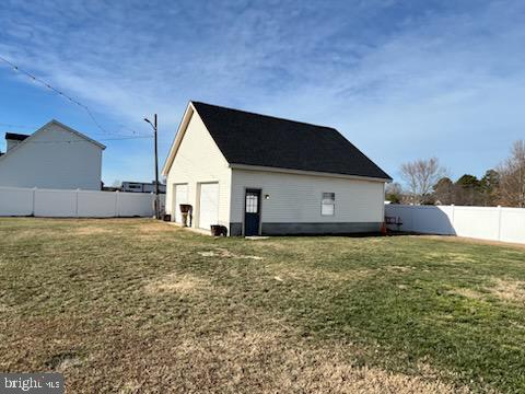 back of house featuring a lawn, a garage, and an outdoor structure