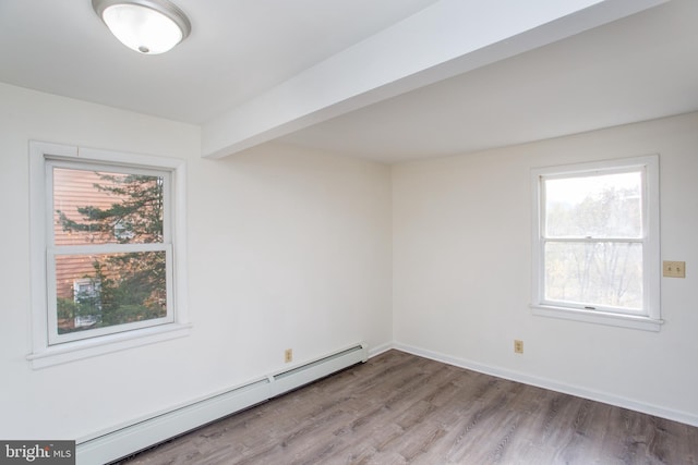 empty room with hardwood / wood-style floors, baseboard heating, and beam ceiling