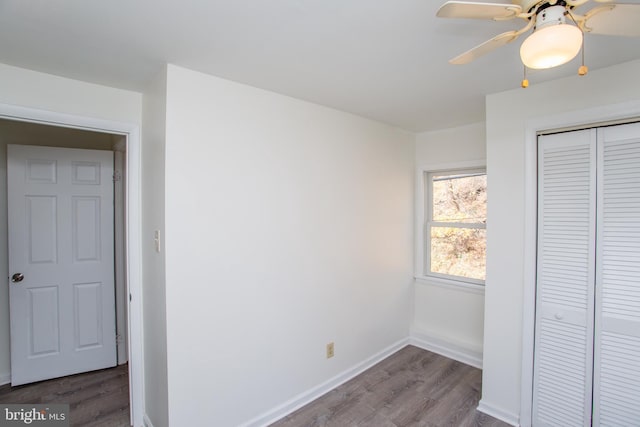 unfurnished bedroom with a closet, ceiling fan, and dark wood-type flooring