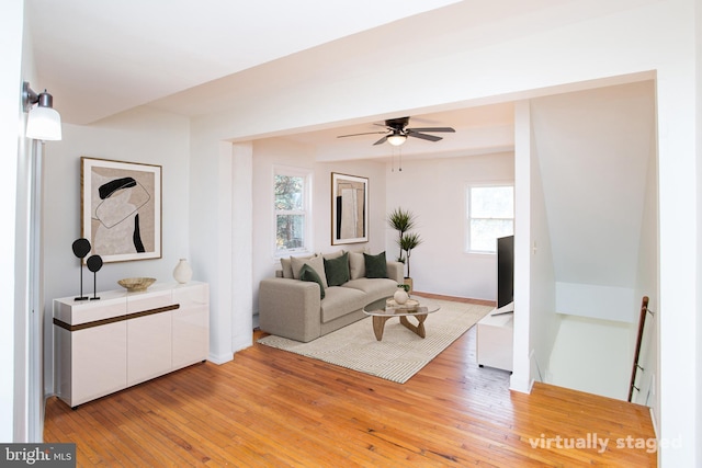 living room with light hardwood / wood-style floors, ceiling fan, and a healthy amount of sunlight