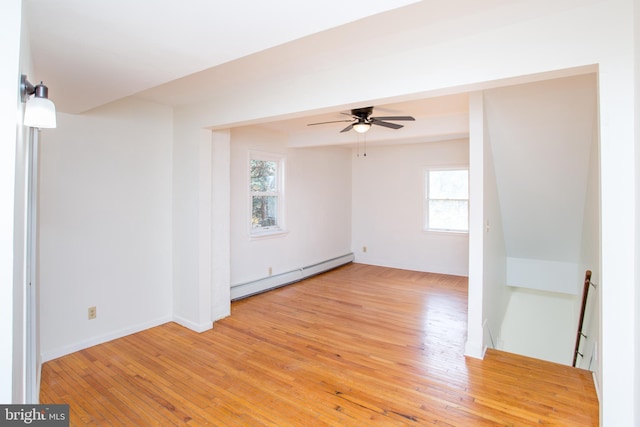 empty room featuring a wealth of natural light, ceiling fan, a baseboard radiator, and light hardwood / wood-style floors