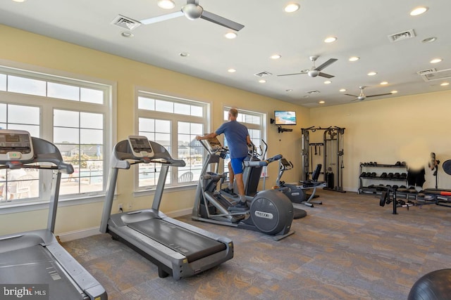 gym with ceiling fan and dark colored carpet