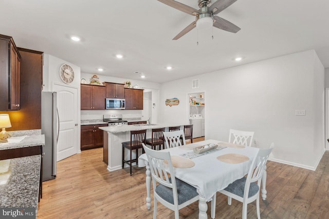 dining room featuring ceiling fan, washer / dryer, and light hardwood / wood-style flooring