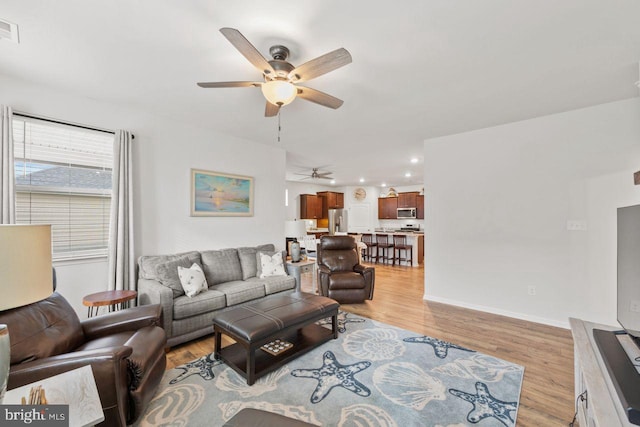 living room with light hardwood / wood-style floors and ceiling fan