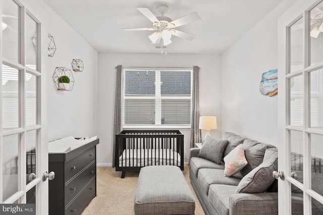 carpeted bedroom with ceiling fan, french doors, and a nursery area