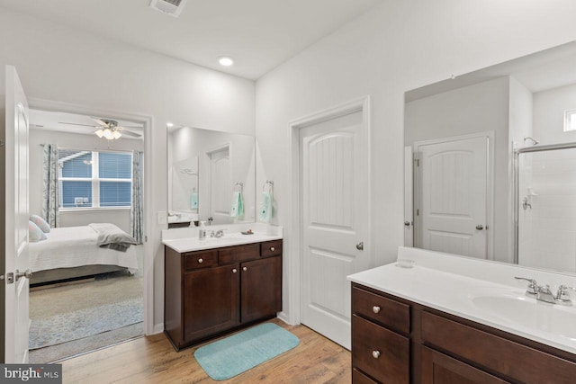 bathroom featuring hardwood / wood-style floors, ceiling fan, walk in shower, and vanity