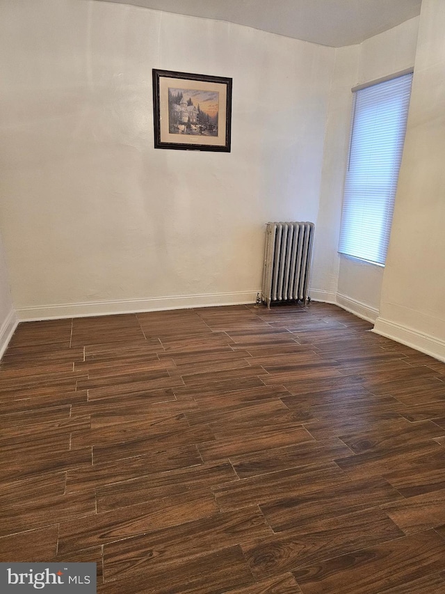 empty room featuring dark hardwood / wood-style flooring and radiator heating unit