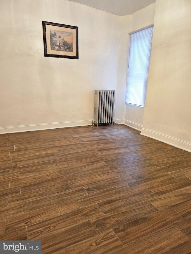 empty room featuring radiator and dark hardwood / wood-style floors