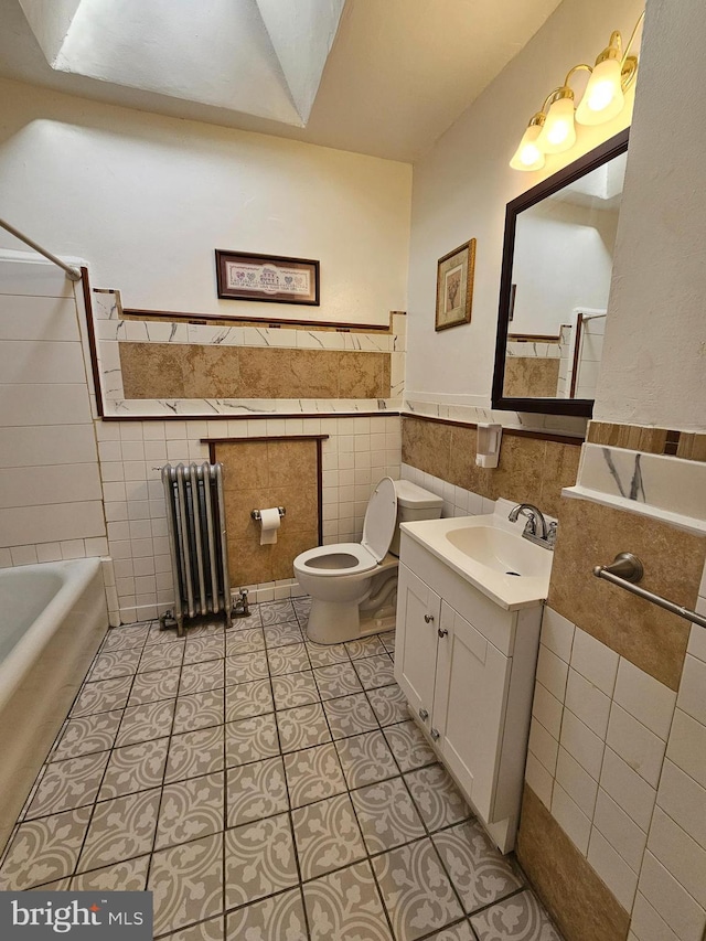 full bathroom with tile patterned floors, vanity, tile walls, radiator heating unit, and toilet