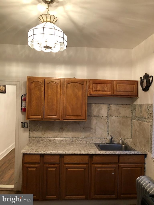 kitchen featuring tasteful backsplash, radiator, sink, and hardwood / wood-style flooring