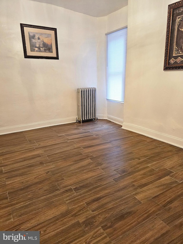 spare room featuring radiator heating unit and dark hardwood / wood-style floors