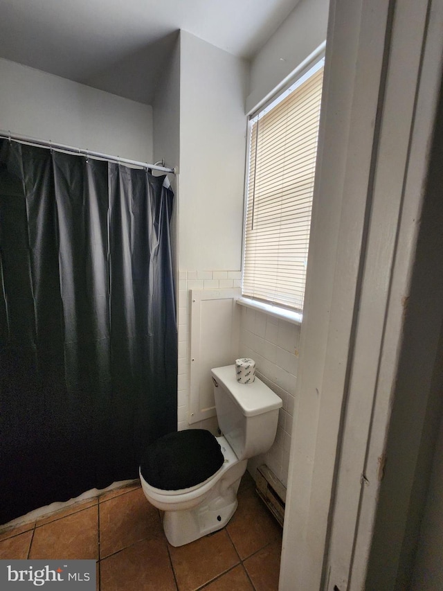 bathroom featuring tile patterned flooring, toilet, tile walls, and a baseboard heating unit