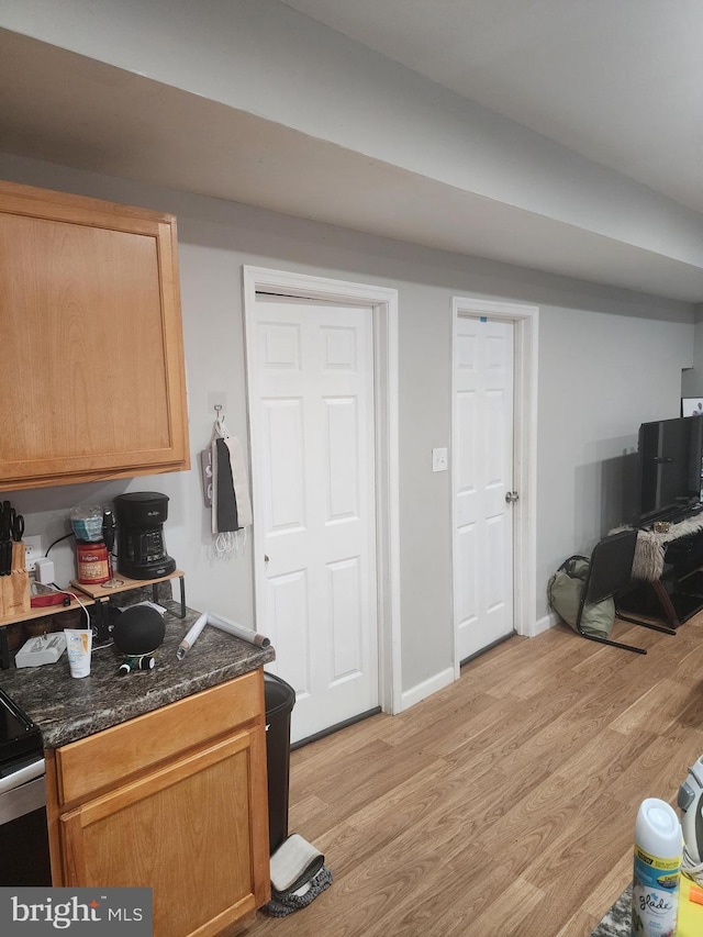 kitchen featuring black electric range oven, dark stone counters, and light wood-type flooring