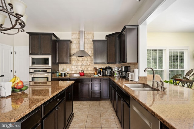 kitchen with sink, wall chimney exhaust hood, decorative backsplash, light stone countertops, and stainless steel appliances