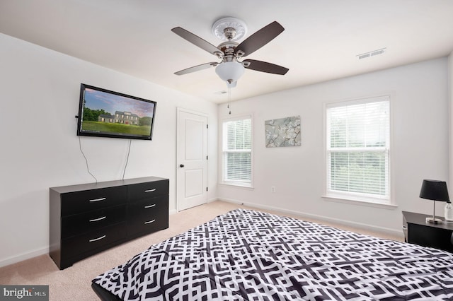 carpeted bedroom featuring multiple windows and ceiling fan