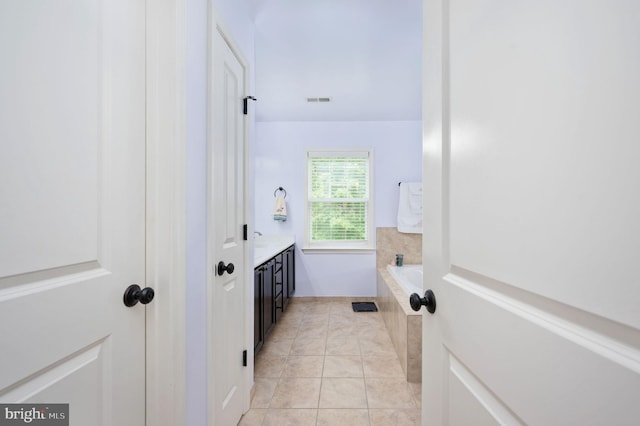 bathroom with tile patterned floors, a bathing tub, and vanity