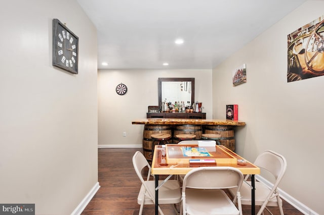 dining room featuring indoor bar and dark hardwood / wood-style floors