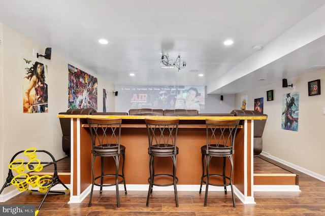 bar with wood-type flooring and an inviting chandelier