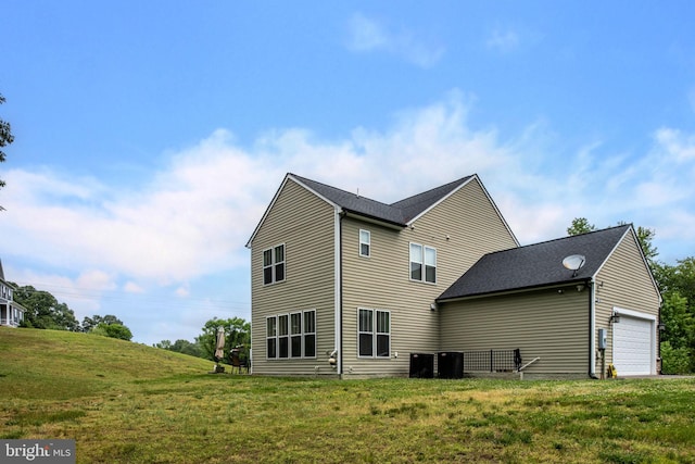 back of property featuring cooling unit, a garage, and a yard