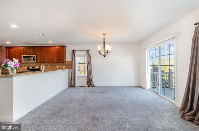 kitchen with tasteful backsplash, decorative light fixtures, a chandelier, appliances with stainless steel finishes, and light colored carpet