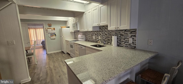 kitchen featuring kitchen peninsula, white appliances, light hardwood / wood-style flooring, and sink