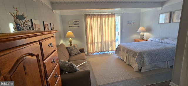 bedroom with beam ceiling, multiple windows, and wooden walls