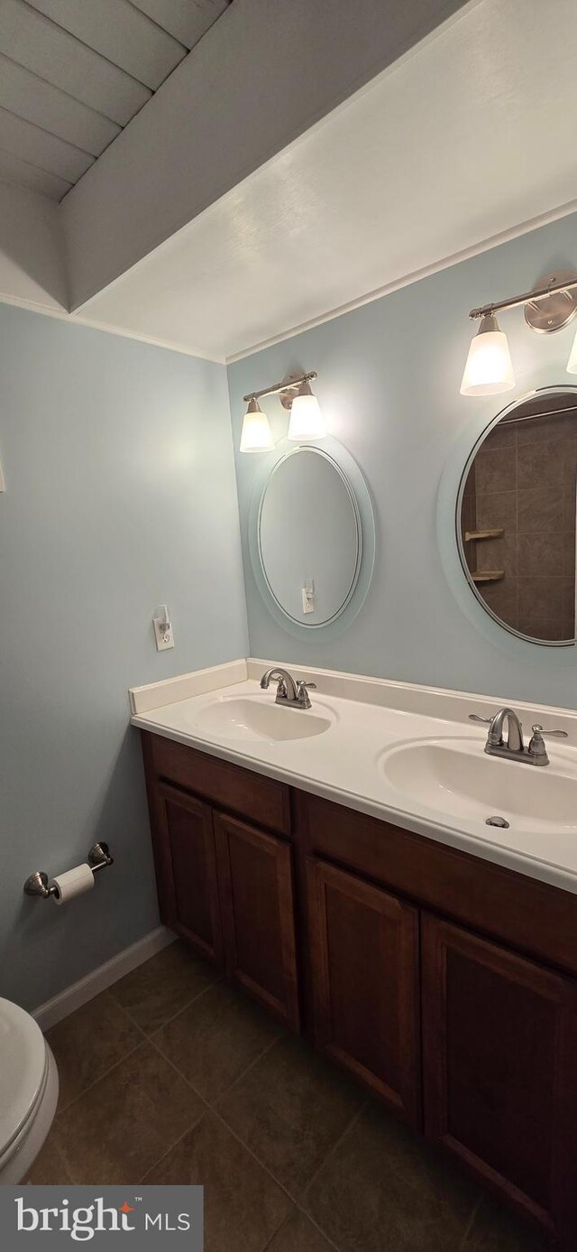 bathroom with toilet, vanity, and tile patterned floors