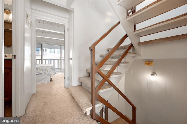 stairs with carpet flooring and beamed ceiling