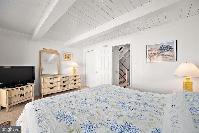 carpeted bedroom with beam ceiling and a closet