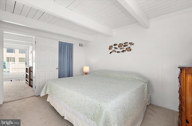 carpeted bedroom featuring beam ceiling and wooden walls