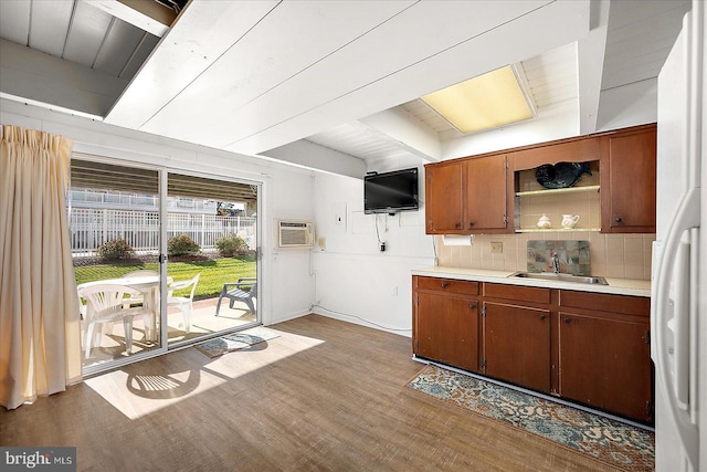 kitchen with a wall mounted air conditioner, light wood-type flooring, tasteful backsplash, sink, and white refrigerator