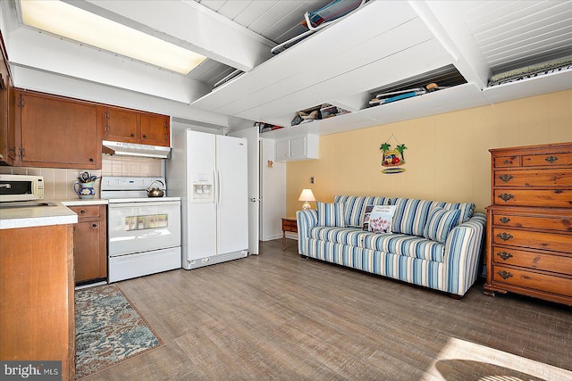 kitchen with beam ceiling, white appliances, and hardwood / wood-style flooring