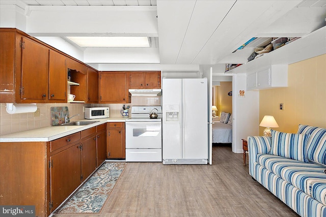 kitchen featuring light hardwood / wood-style floors, white appliances, sink, and tasteful backsplash