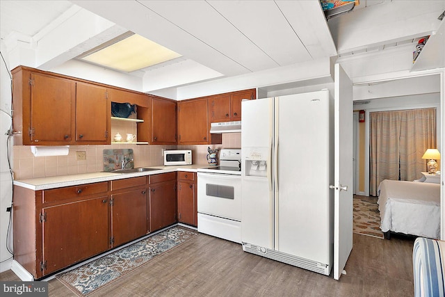 kitchen featuring dark hardwood / wood-style floors, decorative backsplash, white appliances, and sink