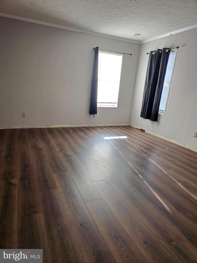 spare room with dark hardwood / wood-style floors, ornamental molding, and a textured ceiling