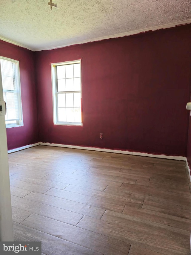 unfurnished room with hardwood / wood-style floors, a textured ceiling, and a wealth of natural light