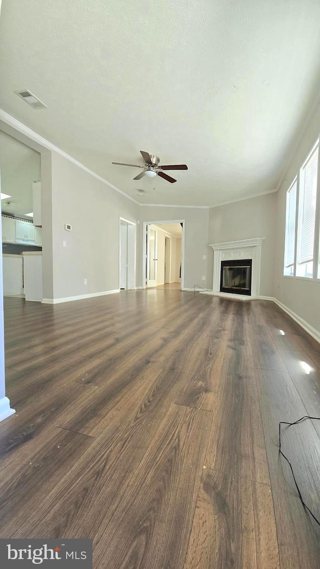 unfurnished living room with ornamental molding, a textured ceiling, ceiling fan, and dark wood-type flooring