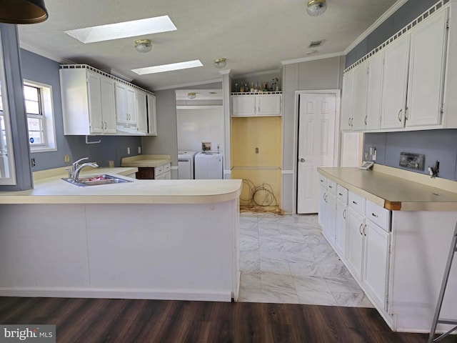 kitchen featuring washer and dryer, hardwood / wood-style flooring, crown molding, and vaulted ceiling with skylight