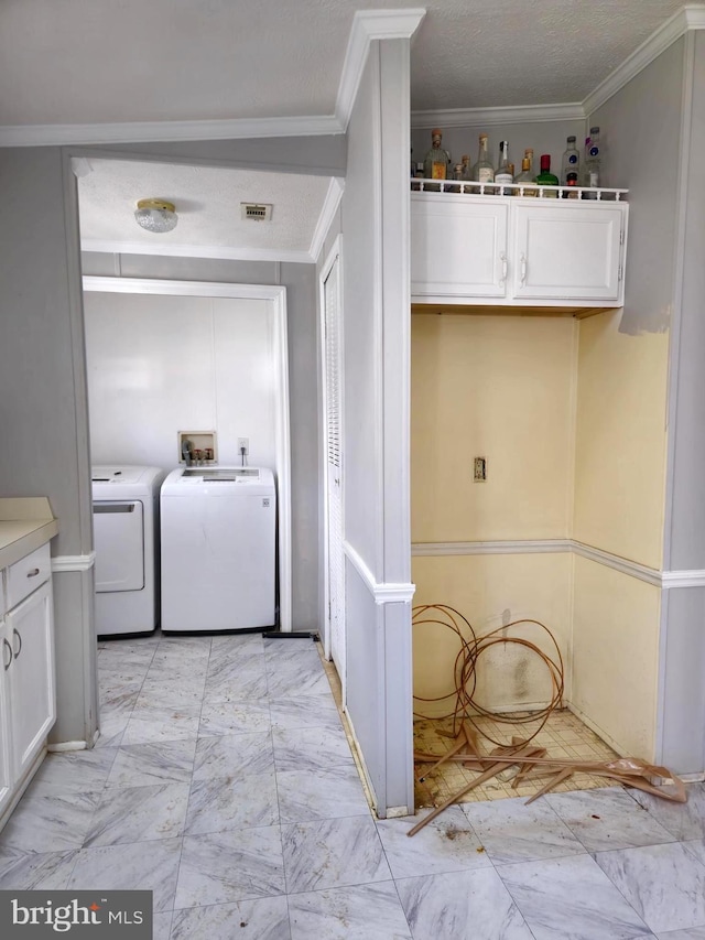 laundry area with a textured ceiling, washing machine and dryer, and crown molding