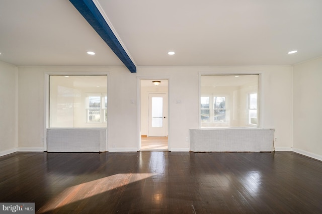 unfurnished living room featuring beamed ceiling, dark hardwood / wood-style floors, and a wealth of natural light