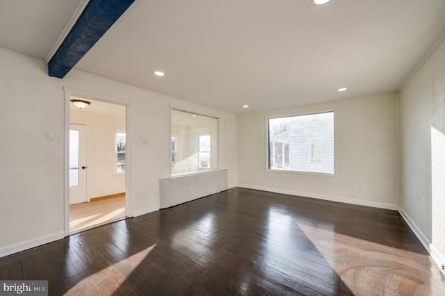 empty room featuring beam ceiling, hardwood / wood-style floors, and ornamental molding