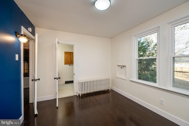 empty room featuring dark hardwood / wood-style floors and radiator