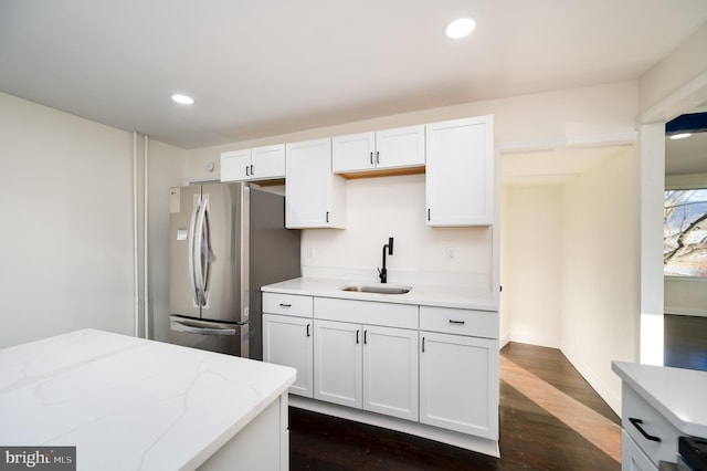 kitchen featuring stainless steel fridge, sink, white cabinets, and dark wood-type flooring