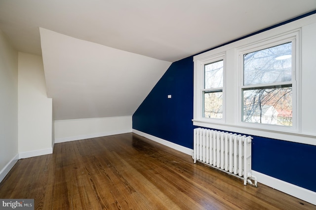 additional living space with hardwood / wood-style floors, radiator, and lofted ceiling