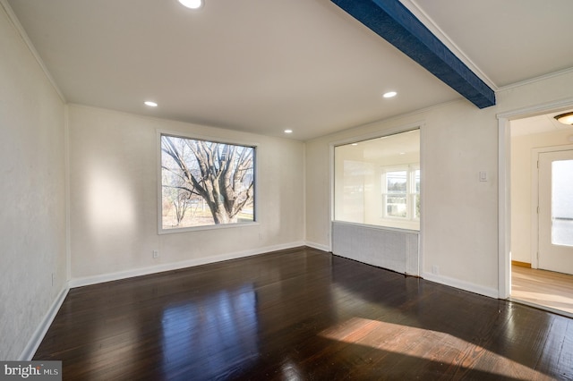 spare room featuring beam ceiling, dark hardwood / wood-style floors, a wealth of natural light, and crown molding