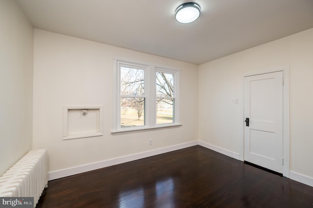 unfurnished room with dark wood-type flooring and radiator