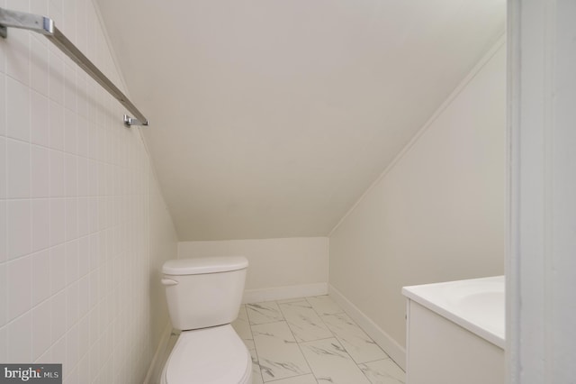 bathroom featuring vanity, lofted ceiling, and toilet